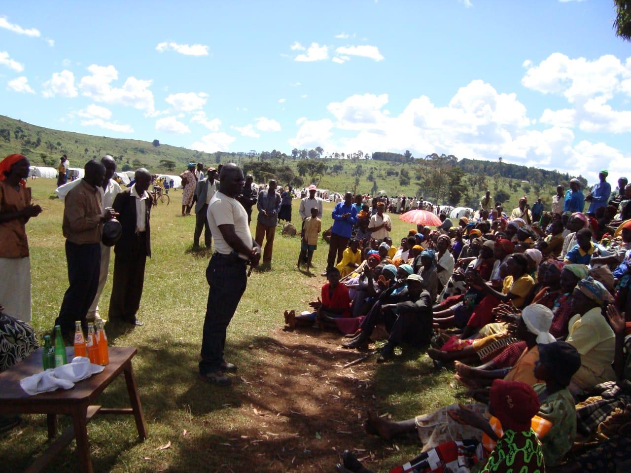 Speaker addressing a community group in an open field